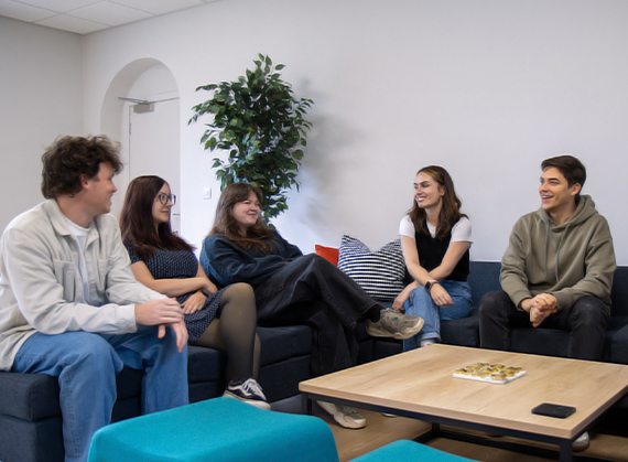 a group of individuals sitting on the sofa and socialising.