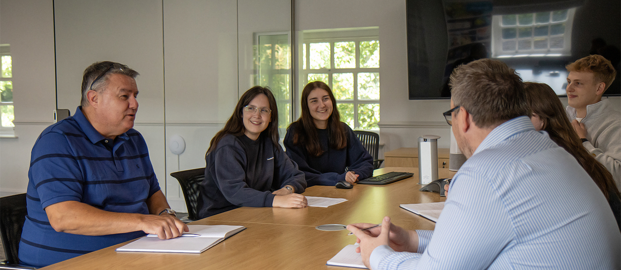 A group of people, discussing their ideas around a boardroom table.