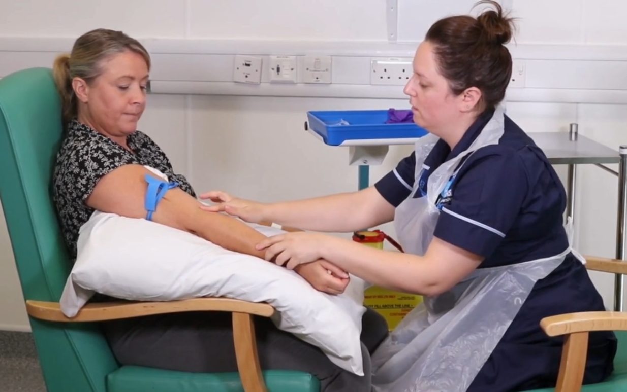 Nurse carrying out a canulation procedure on a patient