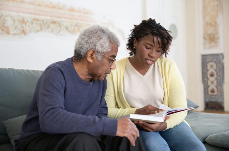 Woman helping adult male with reading